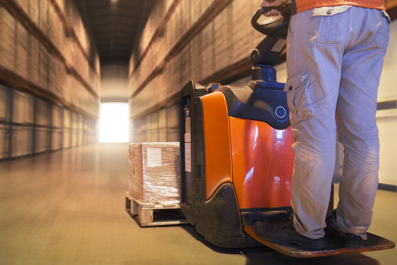 oparaio trabajando con una transpaleta eléctrica en almacén.